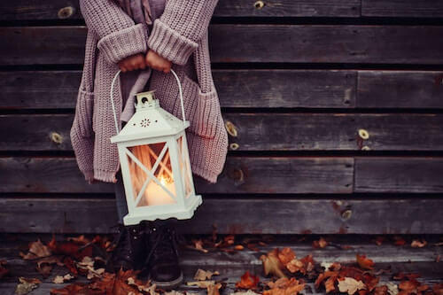 Girl in sweater holding lantern in the autumn equinox.